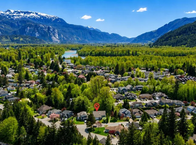 Aerial perspective showcasing a residential area amidst a verdant landscape with prominent mountain ranges