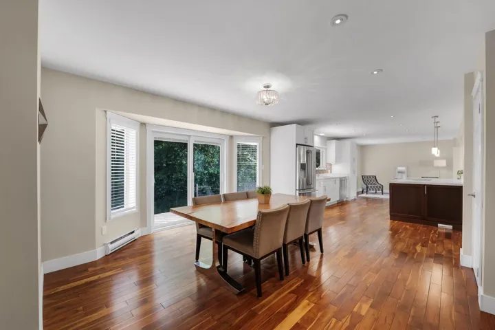 Dining area featuring rich wood-finish flooring, a contemporary chandelier, and large sliding glass doors leading to the exterior
