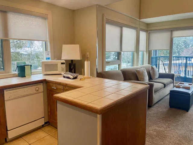 Kitchen featuring tile counters, white appliances, a peninsula, and healthy amount of natural light