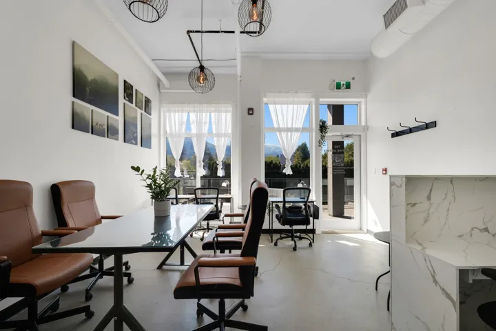Bright interior space featuring multiple large windows, exposed industrial-style ductwork, and concrete flooring