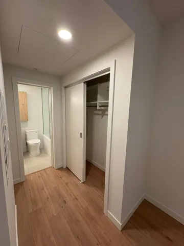 Unfurnished bedroom featuring light wood-style floors, a closet, and ensuite bath