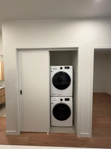 Laundry area featuring light wood-type flooring and stacked washer and clothes dryer