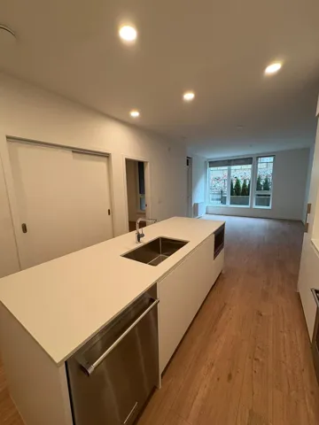 Kitchen with white cabinetry, modern cabinets, stainless steel dishwasher, light wood-style flooring, and an island with sink