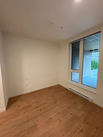 Unfurnished room featuring a baseboard heating unit and hardwood / wood-style floors