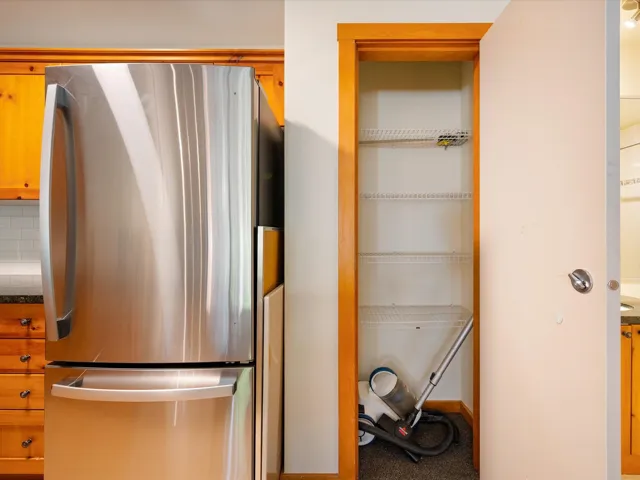 Kitchen with freestanding refrigerator, brown cabinets, and dark countertops