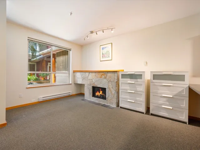 Unfurnished living room with dark carpet, baseboard heating, a fireplace, and track lighting