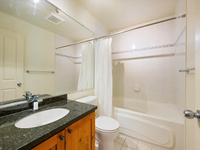 Full bath with shower / bath combo with shower curtain, vanity, and light tile patterned floors