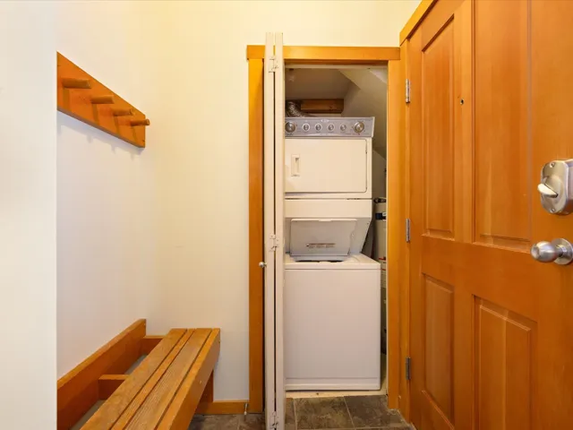 Laundry area featuring stacked washer / dryer and dark tile patterned floors