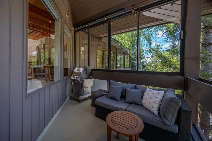 Enclosed patio featuring wall-to-wall windows, a durable concrete floor, wood-paneled exterior siding, and a slatted wood ceiling
