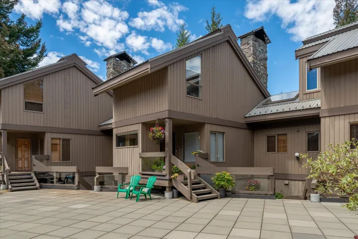 Multi-level exterior featuring brown vertical siding, stone chimneys, and corrugated metal roofing