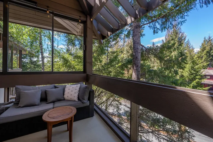Covered balcony featuring a wood-beam ceiling, floor-to-ceiling windows, and wood railing