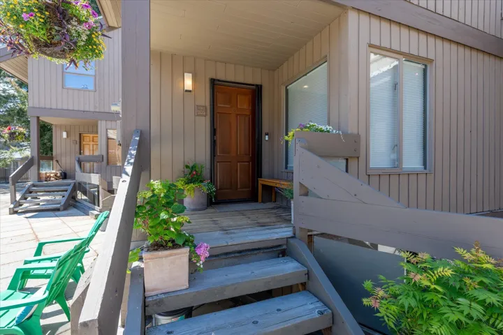 Welcoming entry featuring a rich wood-paneled door, exterior wall sconce, and a wood-slat facade
