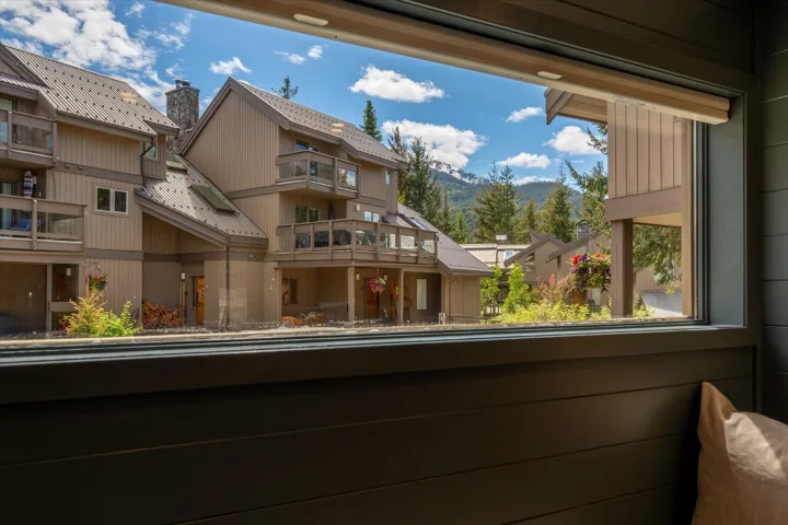 Window framing a mountain landscape with evergreen trees