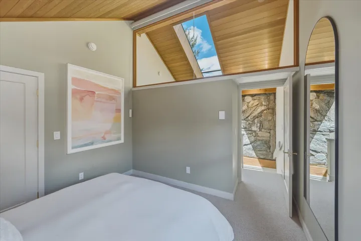 Slanted wood-finish ceiling with a skylight, light gray walls, and carpet flooring