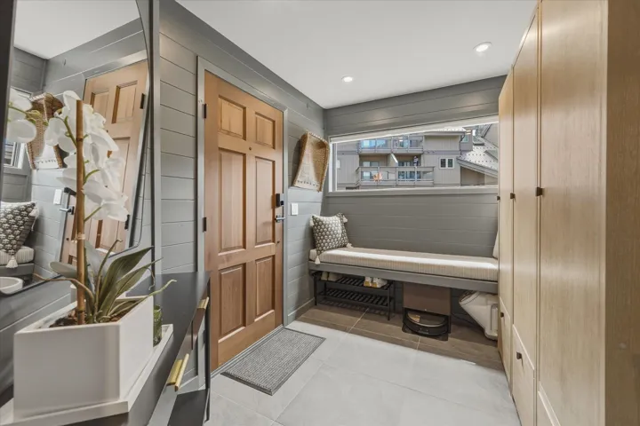 Entryway featuring a natural wood-finish door, light wood-finish built-in cabinetry, and shiplap wall paneling