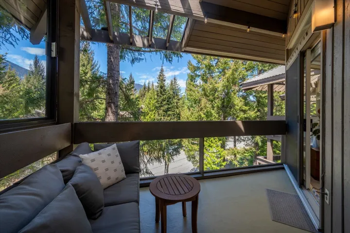 Covered outdoor balcony featuring wood-finish siding, glass panel railing, and recessed lighting