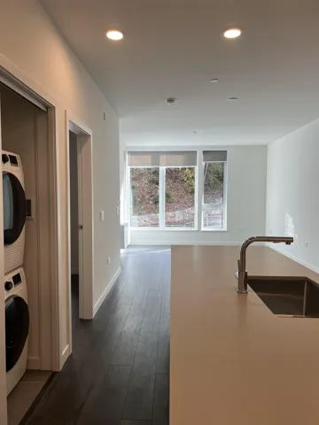 Kitchen with recessed lighting, dark wood finished floors, and stacked washer / dryer