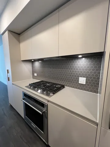 Kitchen with light countertops, modern cabinets, stainless steel appliances, white cabinets, and dark wood-style flooring
