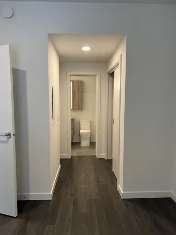 Corridor with dark wood-type flooring and recessed lighting