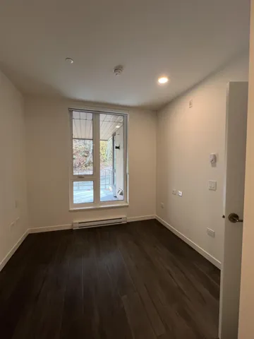 Empty room featuring dark wood-style flooring, a baseboard radiator, and recessed lighting