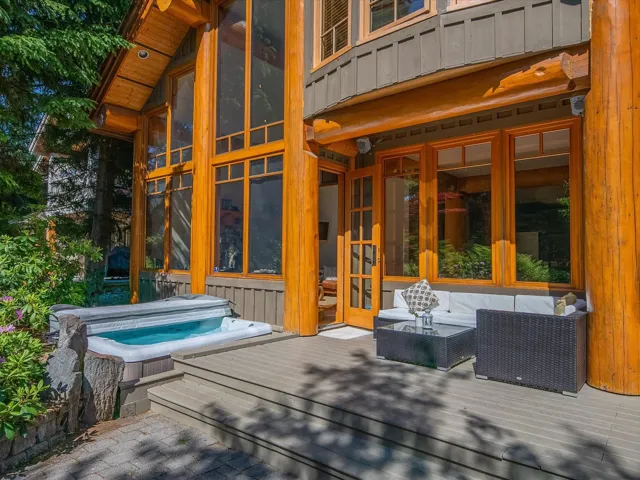 Wooden terrace featuring a covered hot tub and a sunroom
