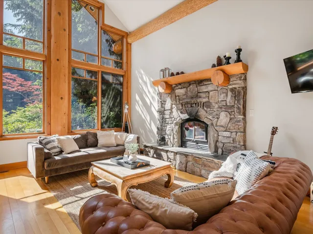 Living room with hardwood / wood-style flooring, a stone fireplace, and high vaulted ceiling