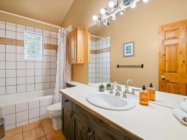 Bathroom featuring tiled shower / bath, vanity, and light tile patterned flooring