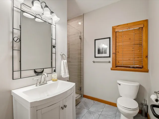 Bathroom featuring vanity, a stall shower, a chandelier, and light tile patterned floors