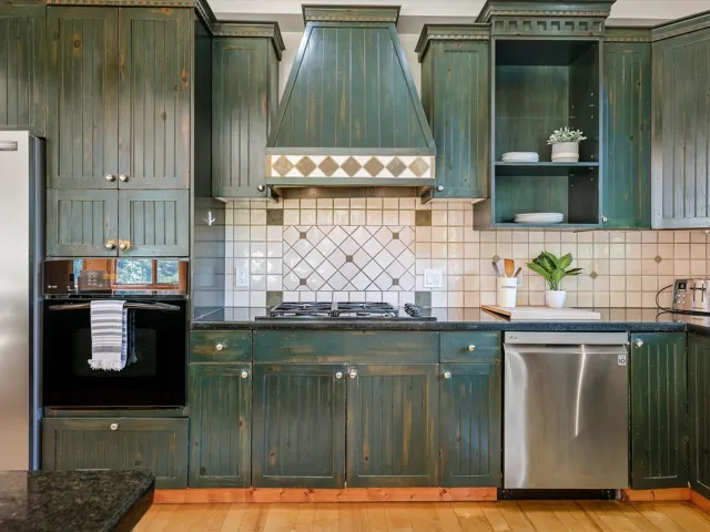 Kitchen featuring green cabinetry, premium range hood, and stainless steel appliances