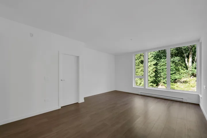 Unfurnished room featuring dark wood-style flooring and baseboard heating