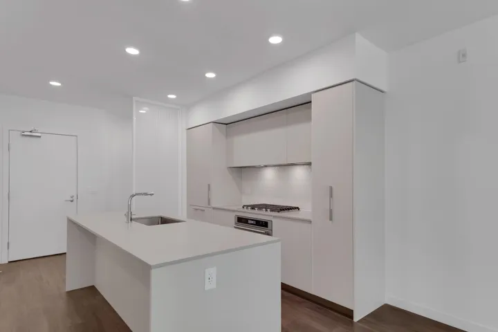 Kitchen featuring modern cabinets, white cabinets, tasteful backsplash, recessed lighting, and a center island with sink