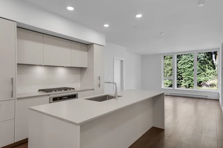 Kitchen with backsplash, light countertops, white cabinets, recessed lighting, and wood finished floors