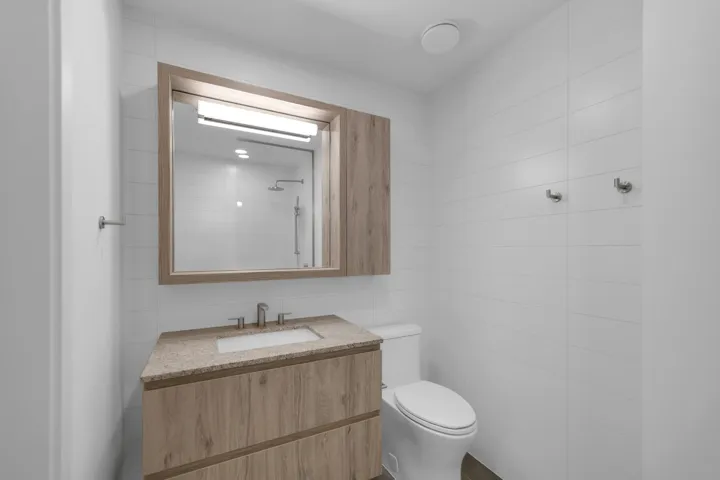 Full bath with tile walls, vanity, and a shower