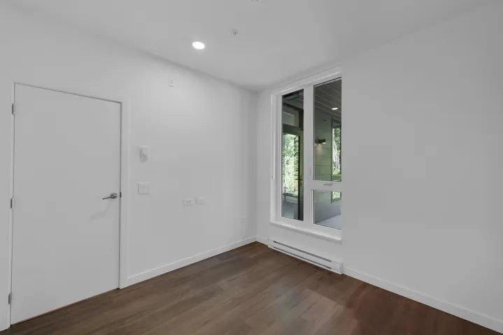 Spare room with dark wood-style floors, a baseboard heating unit, and recessed lighting