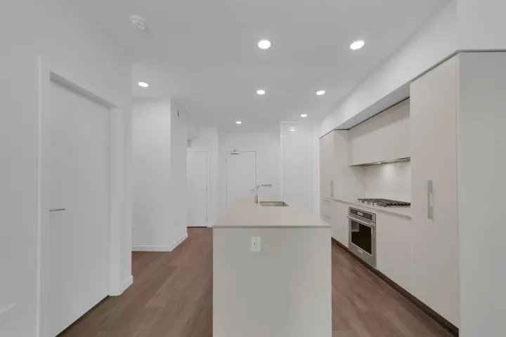 Kitchen with modern cabinets, white cabinets, recessed lighting, wood finished floors, and light countertops