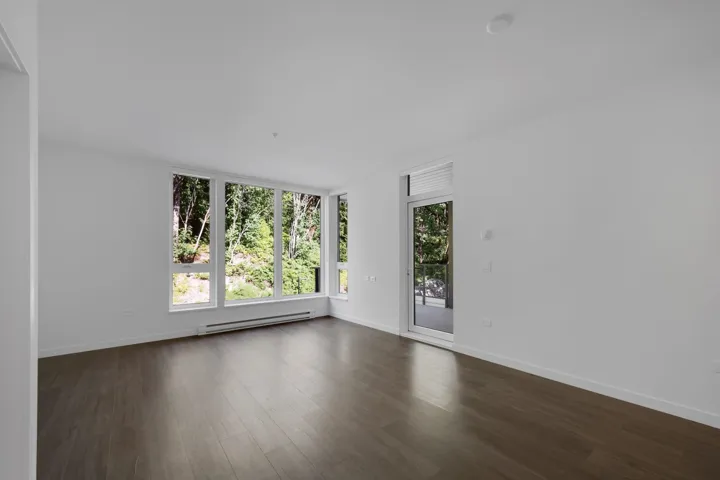 Empty room featuring dark wood finished floors and baseboard heating