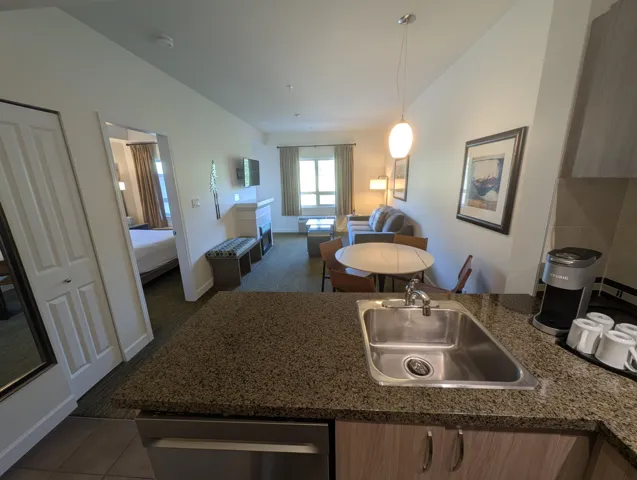 Kitchen featuring a peninsula, open floor plan, stainless steel dishwasher, dark tile patterned flooring, and pendant lighting
