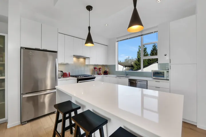 Kitchen featuring appliances with stainless steel finishes, a kitchen bar, white cabinets, modern cabinets, and a center island