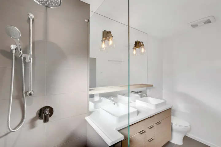 Full bath with double vanity and a tile shower