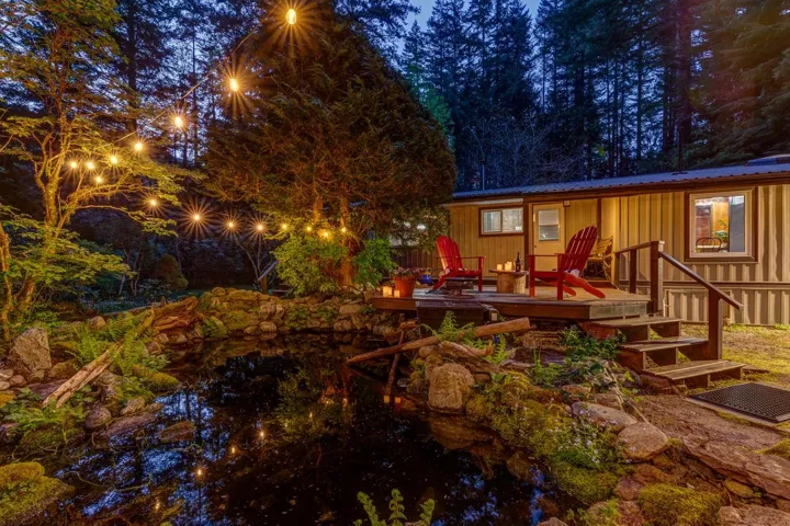 Expansive outdoor living area featuring a wood deck, built-in steps, and a decorative pond surrounded by natural rock and lush greenery