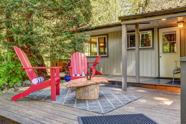 Expansive outdoor deck featuring wood flooring, a partial roof covering, and a built-in exterior light fixture