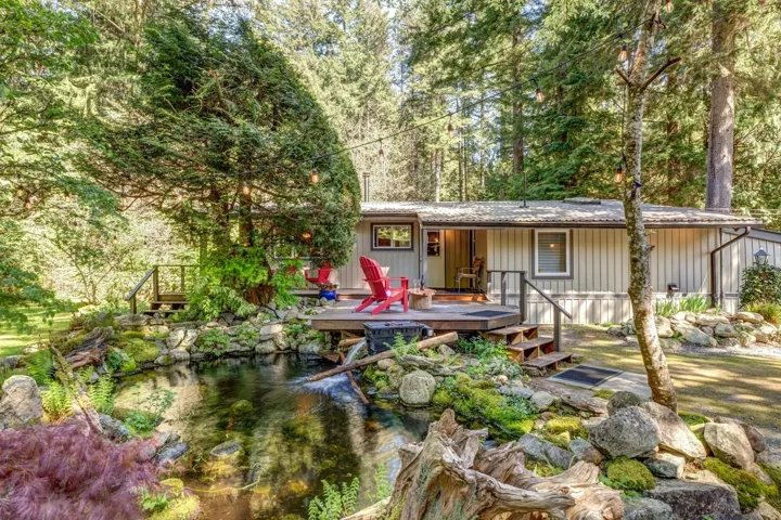 Rear exterior with a wooden deck, integrated steps, and a decorative water feature