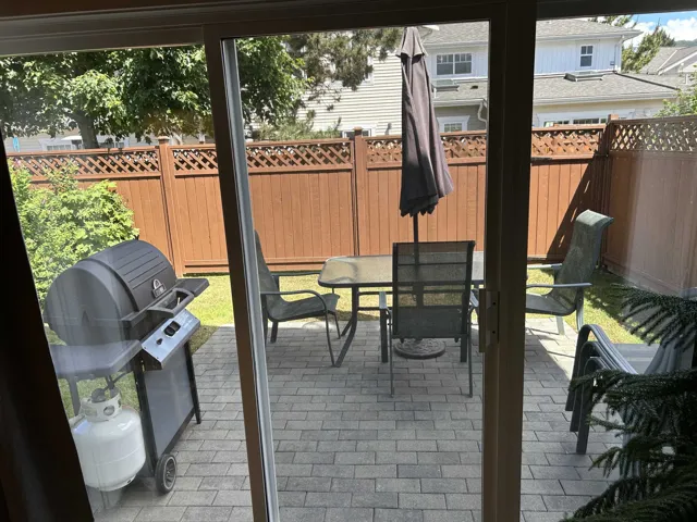 Sliding glass door opening onto a paver patio with a brown lattice-top privacy fence