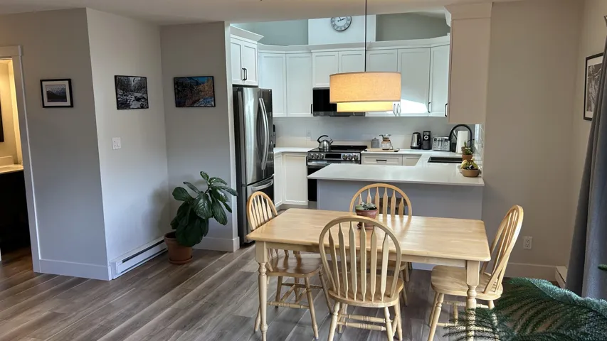 Open-concept dining area with wood-finish flooring, recessed lighting, and a contemporary pendant light fixture