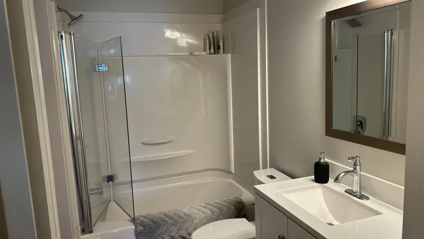 Bathroom featuring a white vanity with integrated sink, chrome faucet, and framed mirror