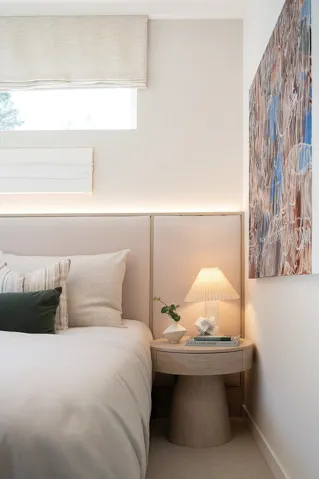 Integrated headboard with backlighting, complementing a round wood-finish nightstand
