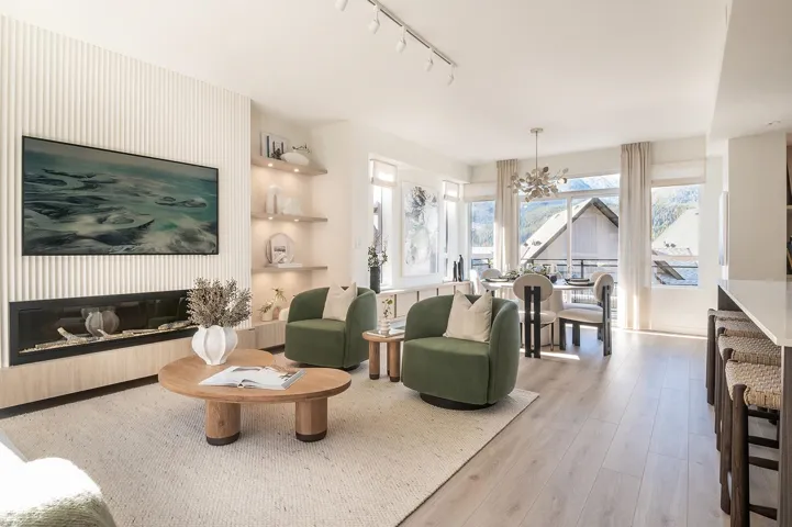 Bright living area featuring a linear fireplace with wood-finish surround, built-in illuminated shelving, and light wood-finish flooring