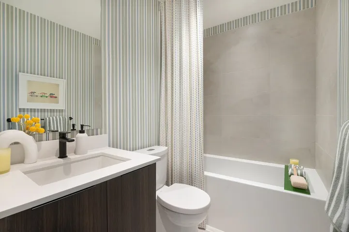 Bathroom featuring a built-in bathtub with a tile surround, a single vanity with an integrated sink, a dark wood-finish cabinet, a white countertop, and a wall-mounted mirror