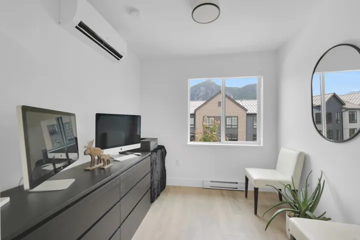 Office with baseboard heating, a wall unit AC, and light wood finished floors