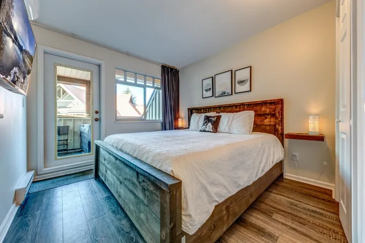 Bedroom with access to outside, baseboard heating, wood finished floors, and baseboards
